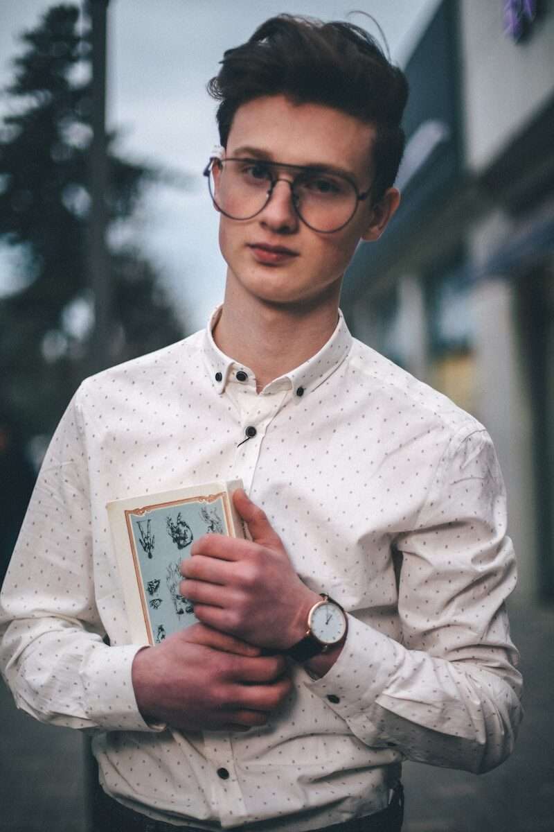 man in white dress shirt holding a book